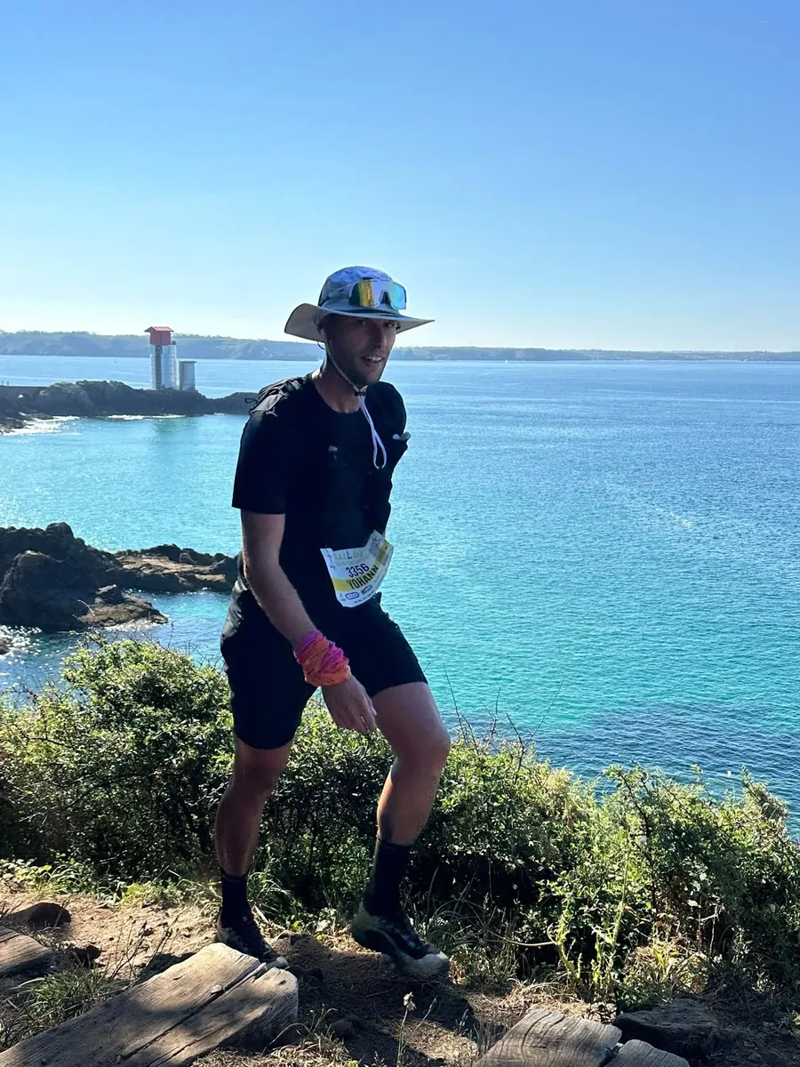 Coureur du club sur un sentier côtier, phare en arrière-plan